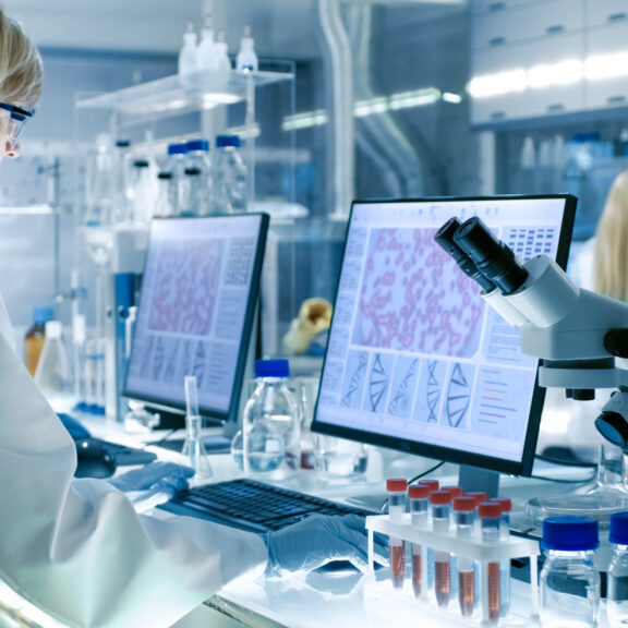 Senior Female Scientist Works with High Tech Equipment in a Modern Laboratory. Her Colleagues are Working Beside Her. Senior Female Scientist Works with High Tech Equipment in a Modern Laboratory. Her Colleagues are Working Beside Her.
