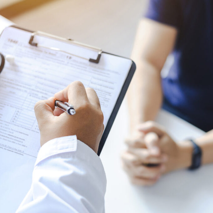 Close-up of a male doctor hand hold a silver pen and showing pad in hospital. Doctor giving prescription to the patient and filling up medical form at a clipboard Close-up of a male doctor hand hold a silver pen and showing pad in hospital. Doctor giving prescription to the patient and filling up medical form at a clipboard