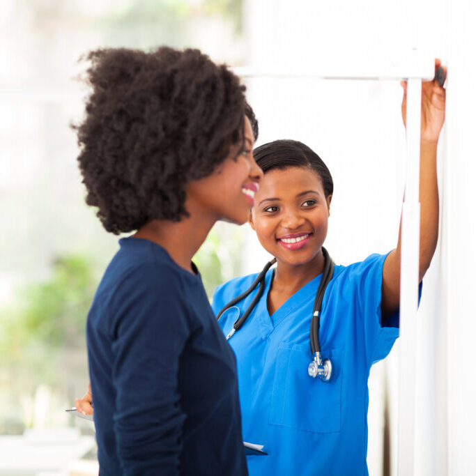 friendly african nurse measuring patient's height